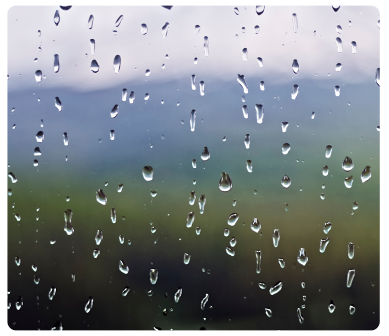 Rain on a window with a blurry landscape, symbolizing a drip marketing strategy.
