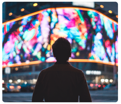 A person admiring vibrant, colorful outdoor signage in a busy city setting.