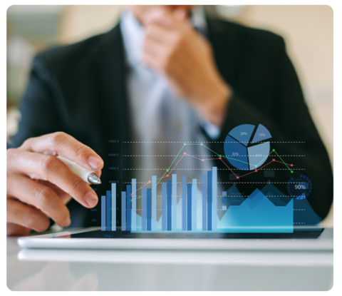 A professionally dressed individual sits at a well-lit desk analyzing printed charts, writing in a notebook, and using a laptop—highlighting the process of uncovering valuable fundraising data insights.